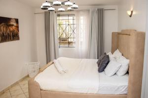 a bedroom with a bed with white sheets and a window at Cozy urban homes in Nakuru +44 photos