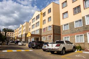 a parking lot with cars parked in front of a building at Cozy urban homes in Nakuru