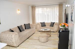 a living room with two couches and a table at Cozy urban homes in Nakuru