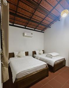 two beds in a room with white walls at Nhà Vườn - Garden homes in Ấp Bến Ké (2) +10 photos