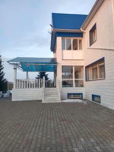 a house with a blue roof on a brick driveway at Усадьба in Kostanay