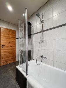 a bathroom with a shower and a bath tub at Talblick - Apartment Hortensie in Losheim +36 photos