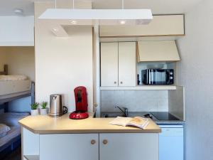 a kitchen with white cabinets and a book on a counter at BLEUE OCEANE - Studio, Piscine commune - U65 in Carnac +3 photos