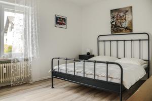 a bedroom with a black bed in a room with a window at Talblick - Apartment Hortensie in Losheim