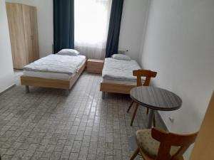 two beds in a room with a table and chairs at Margarethner Appartments in Sankt Margarethen bei Knittelfeld