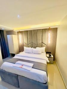 a hotel room with a large bed with white sheets at Emiez Apartment and Hotel in Benin City +71 photos