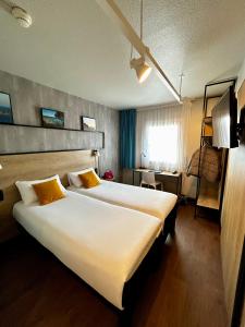 a hotel room with a large white bed with yellow pillows at ibis Saint-Malo Madeleine in Saint Malo +150 photos