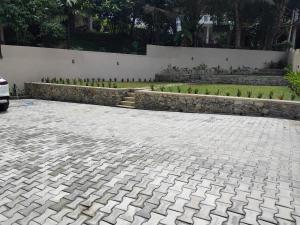 a stone driveway with a garden in the background at Hotel & Restaurant Chingari Pinnawala in Rambukkana