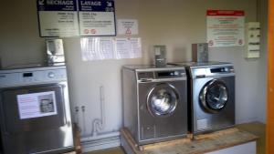 a laundry room with two machines and signs on the wall at Les Clés Nature Studio 41 in Moutiers-sous-Chantemerle
