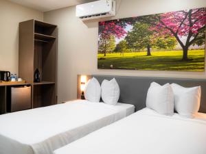 two beds in a hotel room with a painting on the wall at TStays Smart Hotel Courtyard, Gated Modern Stay in Port-of-Spain