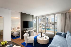 a living room with a blue couch and a bedroom at The YACHT - By Fattal Limited Edition in Herzliya B