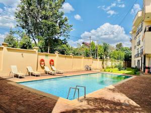 a swimming pool with chairs and a building at JJ Comfort Homes in Arusha