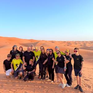 a group of people posing for a picture in the desert at Alghyamcamp in Muntarib +6 photos