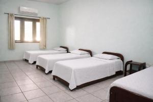 a room with four beds with white sheets and a window at Garden Hotel e Eventos in Benevides