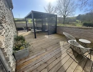 a wooden deck with two chairs and a table at Beudy at Pentrecelyn - A stylish, dog friendly barn conversion with hot tub in Carmarthenshire in Carmarthen