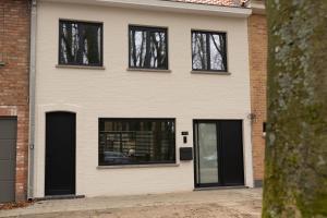 a white house with black doors and windows at Stories Lodewijk en Margaretha in Bruges