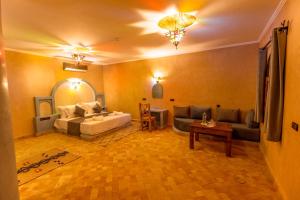 a living room with a bed and a couch at Hotel Sunset Palace Merzouga in Merzouga