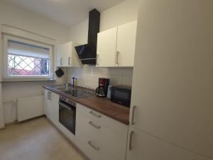 a kitchen with white cabinets and a sink and a microwave at Ferienwohnung Annenblick in Sankt Wendel