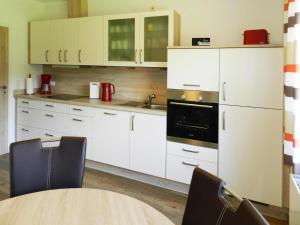a kitchen with white cabinets and a table with chairs at Ferienwohnung Landblick, Rastede in Rastede