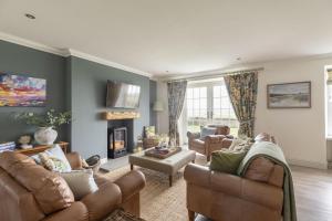 a living room with couches and a fireplace at Greenhead Cottage in Kelso
