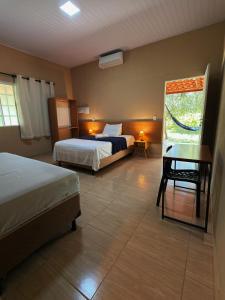 a bedroom with two beds and a table and a window at Pousada Sítio Rupestre Peruaçu in Januária +60 photos
