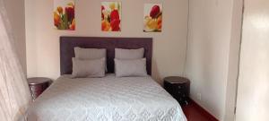 a bed in a bedroom with two paintings on the wall at Epic touch B&B in Sandton