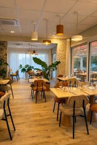 a restaurant with wooden tables and chairs and windows at Hotel Maison Forge - Ex Hotel ASTORIA- Saint Etienne-Centre des Congrès- in Saint-Étienne