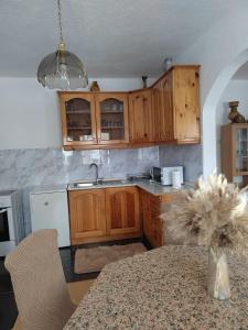 a kitchen with wooden cabinets and a table with a vase at Apartman Lara in Kupres