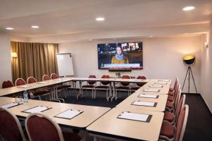 a conference room with tables and chairs and a screen at Hotel Maison Forge - Ex Hotel ASTORIA- Saint Etienne-Centre des Congrès- in Saint-Étienne