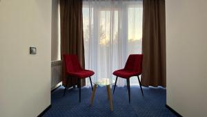 two red chairs and a table in front of a window at Optima Collection Kamianske in Kamianske