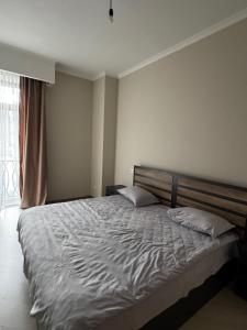 a bedroom with a large bed with white sheets and a window at AlvinaMI in Tsaghkadzor