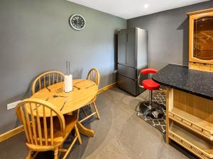 a kitchen with a wooden table and chairs and a refrigerator at Orcadians in Sellindge