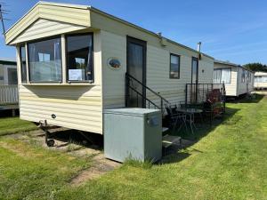 a mobile home with a porch and a table at 6 berth static in Skegness in Chapel Saint Leonards