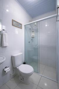 a bathroom with a toilet and a glass shower at Pousada Familiar I 5 min de carro do centrinho I Piscina, café e estacionamento in Paraty