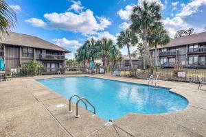 a swimming pool with palm trees and buildings at Golfer's Getaway! Modern Diamondhead Condo in Diamondhead