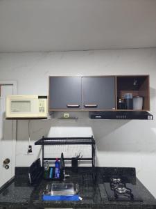 a kitchen with a stove and a microwave at Studio Aconchegante in Lins