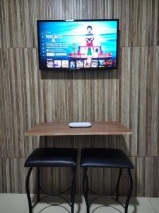 a tv on a wall with two chairs and a table at Studio Aconchegante in Lins +4 photos