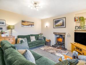 a living room with a green couch and a fireplace at Carrie's Gate in Coniston