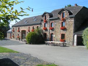 a stone building with red flowers on the windows at Gite 2 de Renuamont in Sainte-Ode