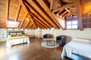 a bedroom with a bed and two chairs and wooden ceilings at Palacio de Arce in Puente Arce