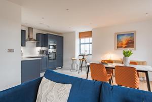 a living room with a blue couch and a kitchen at iDeal Apartment by Keepers Cottages in Deal