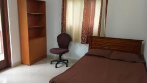 a bedroom with a bed and a chair next to a window at Spacious 4BR Green Court Villa for 8-10 Guests AC & Hot Water Thalawathugoda in Talawatugoda