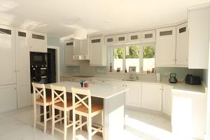 a kitchen with white cabinets and a island with stools at The Old Post Office Holiday Home, Dunmore in Galway