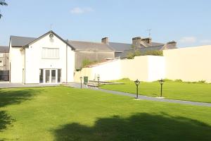 a large white house with a green lawn at The Old Post Office Holiday Home, Dunmore in Galway