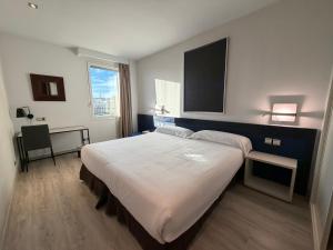 a bedroom with a large bed and a desk at Amura Alcobendas in Alcobendas
