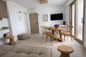 a living room with a table and chairs and a tv at REYA suites in Aliki