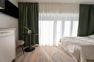 a bedroom with a bed and a window with green curtains at BLI One in Vilsbiburg