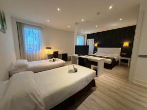 a hotel room with two beds and a desk at Amura Alcobendas in Alcobendas
