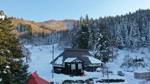 a small cabin with snow on the roof at 森ノ間 大谷荘 in Myoko