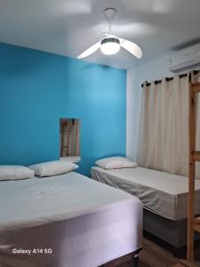 two beds in a room with a blue wall at Casa em Prado bahia in Prado +6 photos
